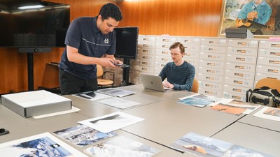 Two men work in a library archive.
